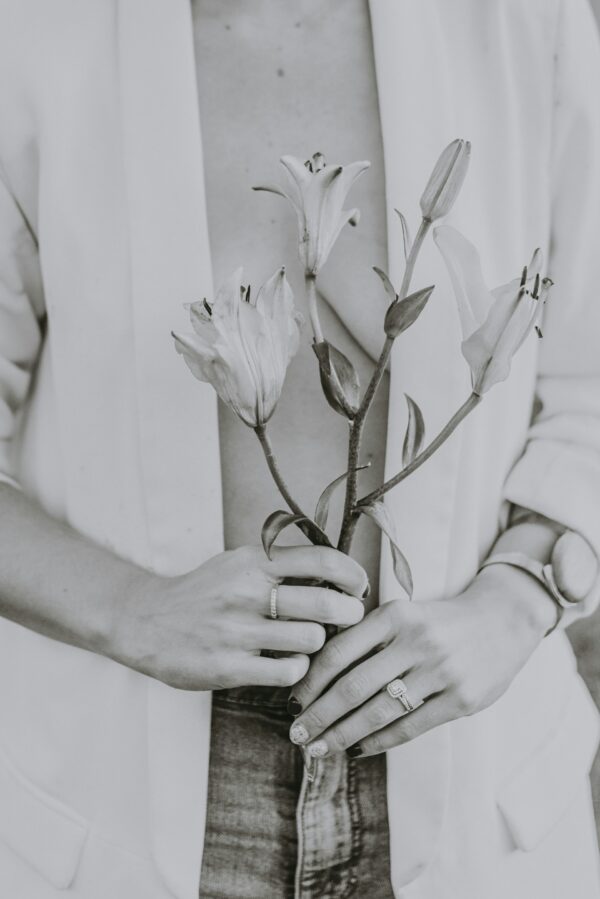 Grayscale photo of a person holding a flower