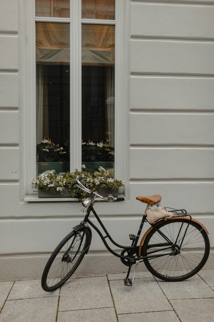 Black old bike parked beside white wall